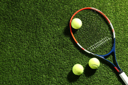 Tennis racket and balls on green grass, flat lay. Space for textの写真素材