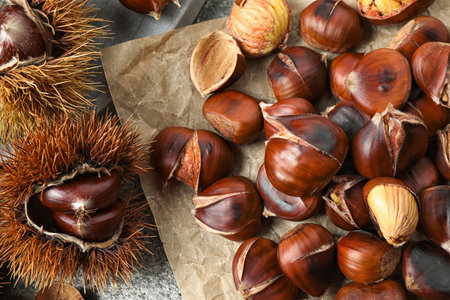 Delicious roasted edible chestnuts on gray table, flat layの写真素材