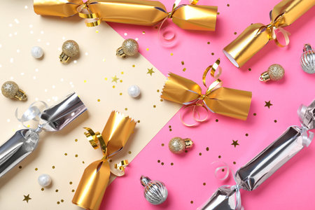 Christmas crackers with decorations and shiny confetti on color background, flat layの写真素材