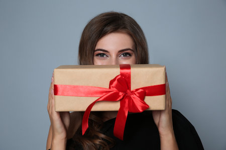 Happy woman with gift box on gray background. christmas partyの写真素材