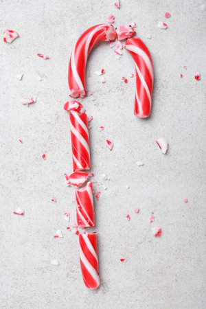 Crushed Christmas candy cane on gray background, flat layの写真素材