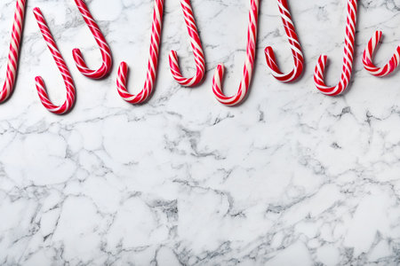 Sweet Christmas candy canes on white marble background, flat lay. Space for textの写真素材