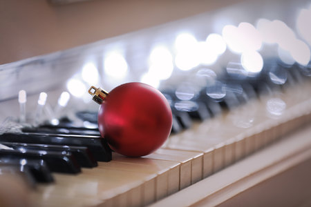 Beautiful red bauble and fairy lights on piano keys, closeup. christmas musicの写真素材