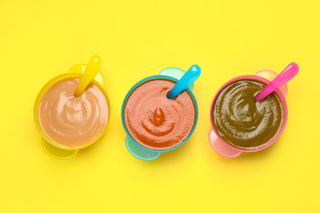 Healthy baby food on yellow background, flat layの写真素材