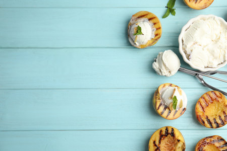 Delicious grilled peaches with ice cream and mint on light blue wooden table, flat lay. Space for textの写真素材