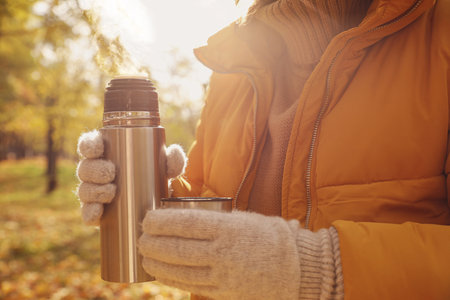 Woman with metallic flask and cap outdoors, closeupの写真素材