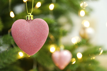 Beautiful heart shaped holiday bauble hanging on Christmas tree, closeup. Space for textの写真素材