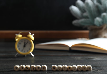 Cubes with phrase Winter Holidays on black wooden table in classroom. Space for textの写真素材