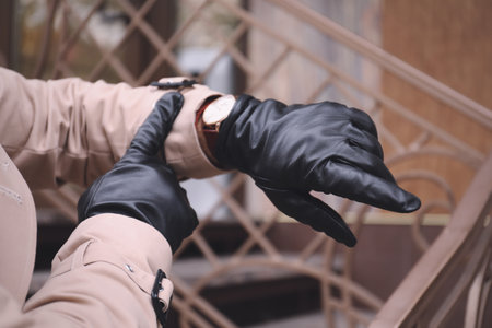 Stylish man in black leather gloves looking at his watch outdoors, closeupの写真素材