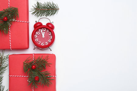 Flat lay composition with Christmas gift and alarm clock on white background, space for text. boxing...