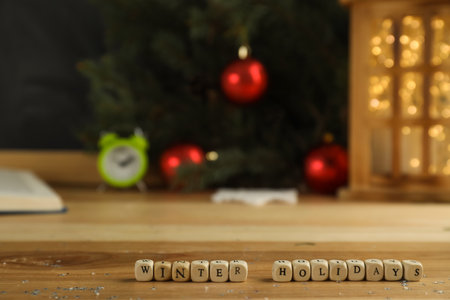 Wooden cubes with phrase Winter Holidays and blurred Christmas decor on background. Space for textの写真素材