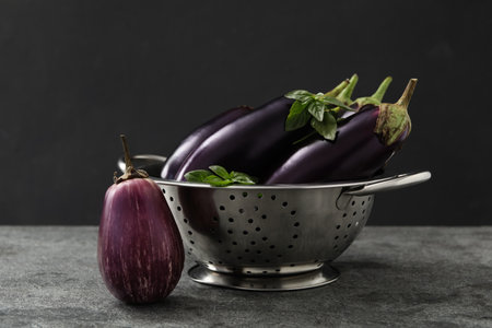 Ripe purple eggplants and basil on gray tableの写真素材