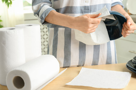 Woman wiping ceramic bowl with paper towel indoors, closeupの写真素材