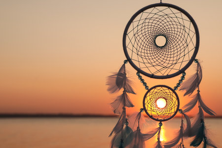 Beautiful handmade dream catcher near the river at sunset. Space for textの写真素材