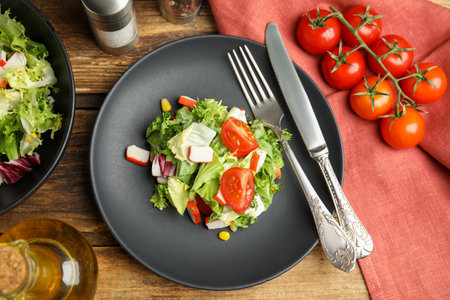 Delicious salad with crab sticks and tomatoes on wooden table, flat layの写真素材
