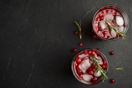 Tasty refreshing cranberry cocktail with rosemary on black table, flat lay. Space for textの写真素材