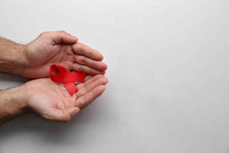 Man holding red awareness ribbon on white background, top view with space for text. World AIDS...