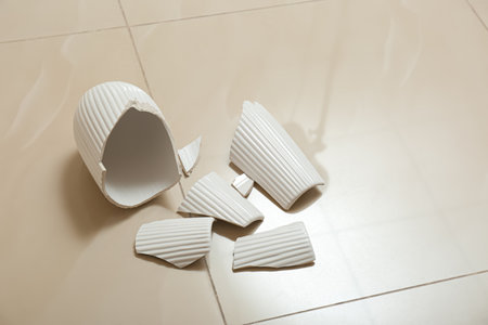 Broken white ceramic vase on floor indoorsの写真素材