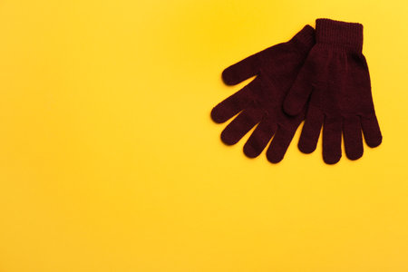 Pair of stylish woolen gloves on yellow background, flat lay. Space for textの写真素材