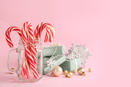 Candy canes, gift boxes and Christmas decor on pink background, space for textの写真素材