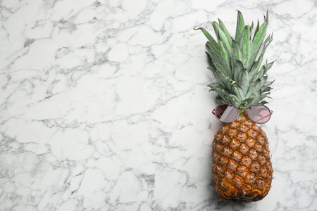 Top view of pineapple with sunglasses on white marble background, space for text. creative conceptの写真素材