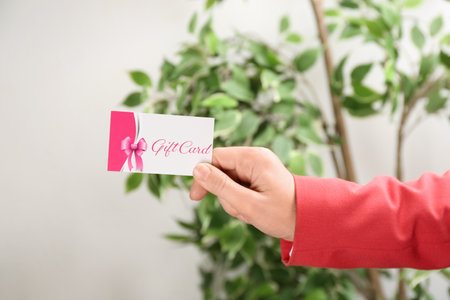 Woman with gift card on blurred background, closeupの写真素材