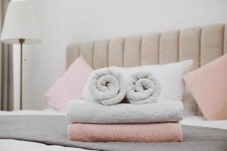 Soft clean towels on bed in roomの写真素材