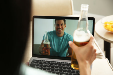 Friends drinking beer while communicating through online video conference at home. social distancing during coronavirus pandemicの写真素材