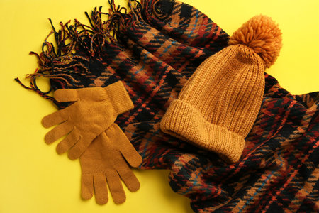 Stylish gloves, scarf and hat on yellow background, flat layの写真素材