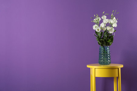 Elegant vase with eustoma flowers on table near purple wall. Space for textの写真素材