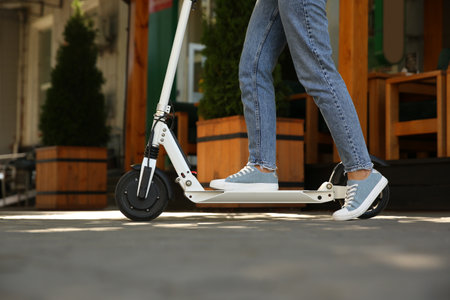 Woman riding electric kick scooter outdoors, closeup