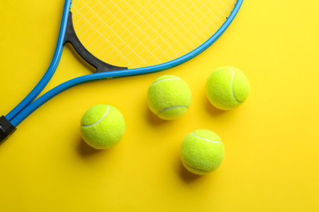 Tennis racket and balls on yellow background, flat lay. sports equipmentの写真素材