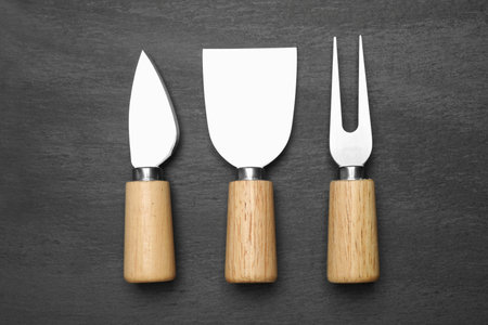Cheese knives and fork on black background, flat layの写真素材