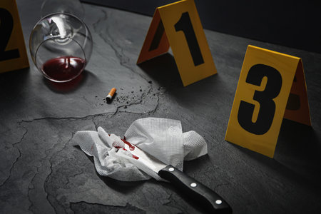 Crime scene markers and evidence on black background, closeup