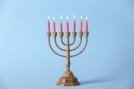 Golden menorah with burning candles on light blue backgroundの写真素材