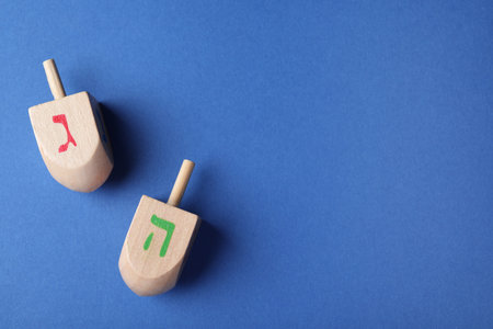 Hanukkah traditional dreidels with letters Gimel and He on blue background, flat lay. Space for textの写真素材