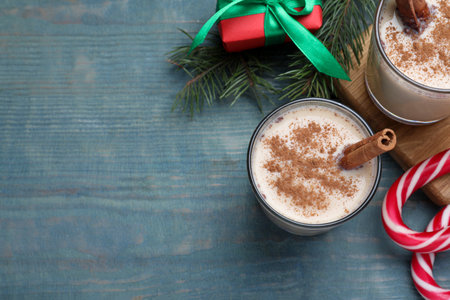 Delicious Christmas liqueur on blue wooden table, flat lay. Space for text