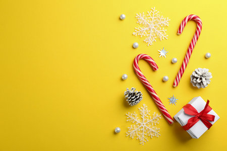 Flat lay composition with candy canes and Christmas decor on yellow background. Space for textの写真素材