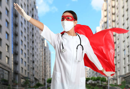 Doctor dressed as superhero on city background. Medical workers fighting dangerous diseasesの写真素材