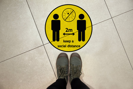 Keep social distance as a preventive measure during coronavirus outbreak. Yellow warning sign on...