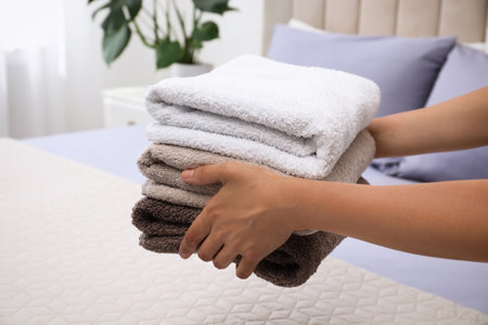 Woman putting Soft clean terry towels on bed, closeupの写真素材