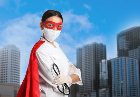 Doctor dressed as superhero on city background. Medical workers fighting dangerous diseasesの写真素材