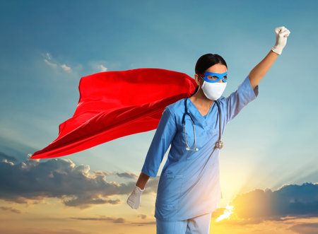 Medical workers fighting dangerous diseases. Doctor dressed as superhero posing against skyの写真素材