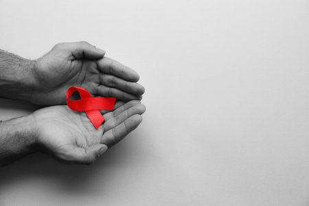 World AIDS disease day. Man holding red awareness ribbon on white background, top view with space for textの写真素材