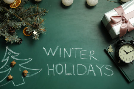 Flat lay composition with text Winter Holidays and Christmas decor on green chalkboardの写真素材