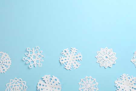 Many paper snowflakes on light blue background, flat lay. Space for textの写真素材