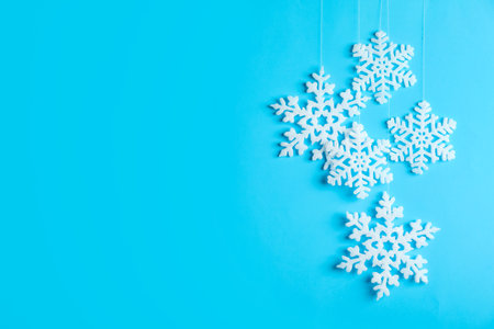 Beautiful decorative snowflakes hanging on light blue background, space for textの写真素材
