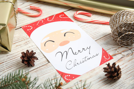 Christmas card and pine cones on white wooden background, closeup