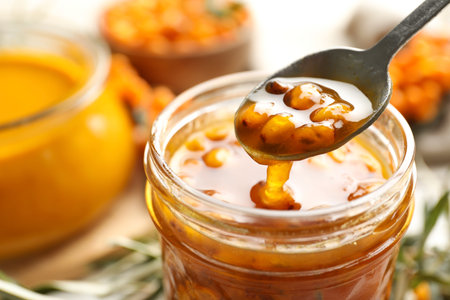 Spoon with delicious sea buckthorn jam over jar, closeupの写真素材