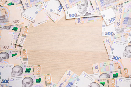 Frame of Ukrainian money on wooden background, flat lay. Space for textの写真素材